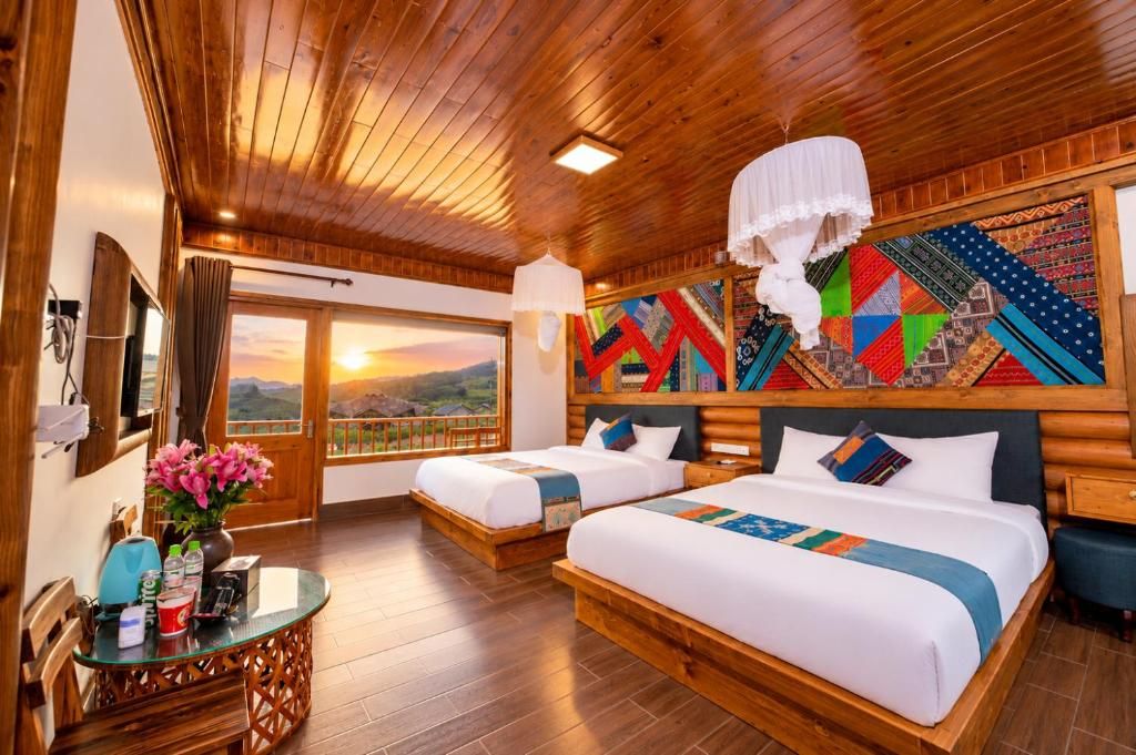 Une chambre d’hôtel avec deux lits, un plafond en bois, une grande fenêtre donnant sur un beau paysage et une décoration murale colorée.