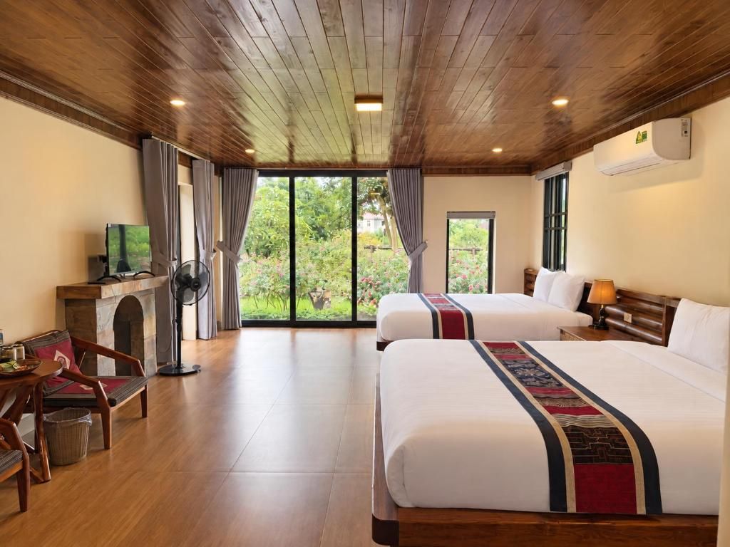 Habitación de hotel con dos camas, televisión, chimenea y vistas a zonas verdes.