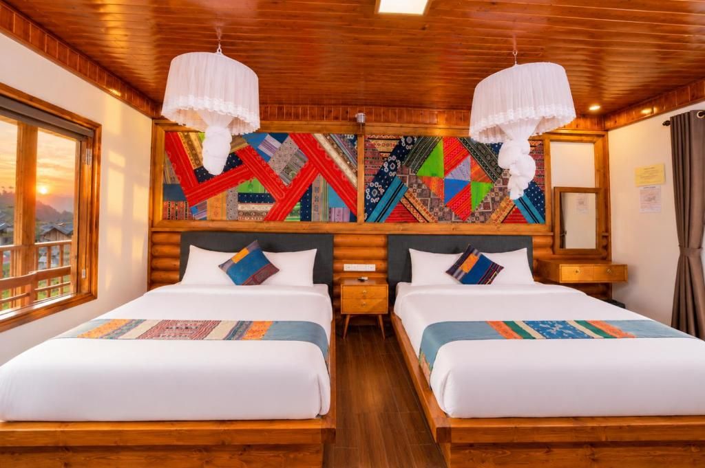 A double room with two beds, wooden headboards, a large window, and a colorful geometric wall art piece.