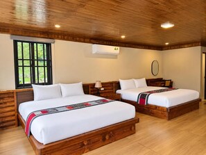 A hotel room with two wooden beds, a window with black frames, and a ceiling with wooden beams. - Stone Garden Resort & Spa (Ta Phin)