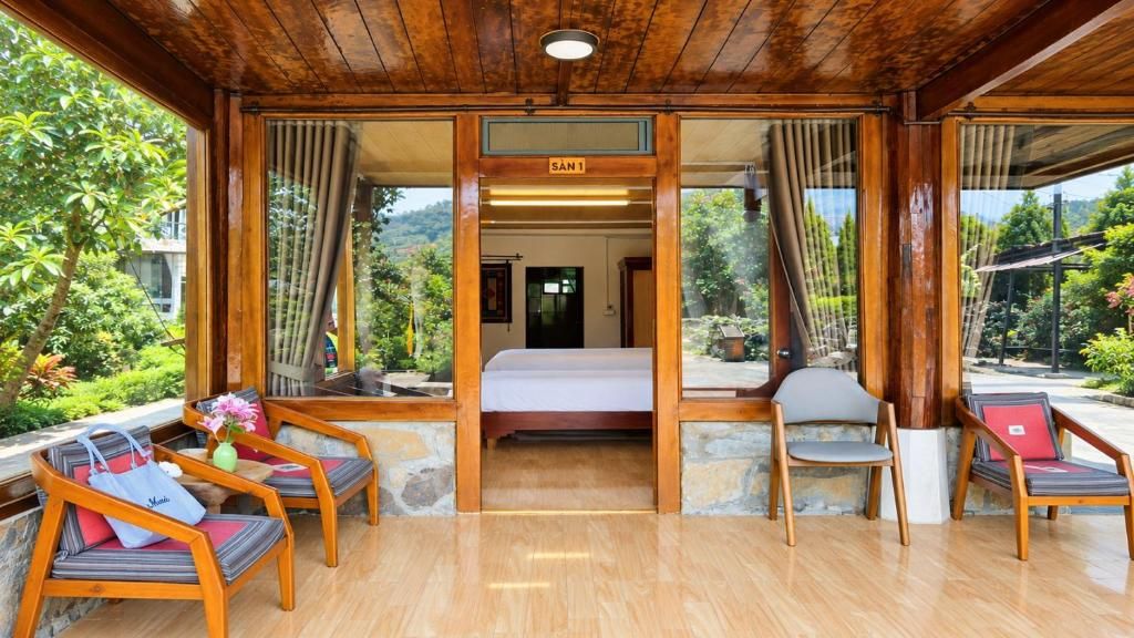 A room with a bed, wooden furniture, and a view of greenery.