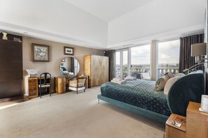 Een moderne slaapkamer met een groot bed, een bureau, een kledingkast en uitzicht op de stad.