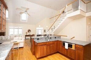 Una cocina amplia con una isla grande, armarios de madera y una escalera que conduce a un nivel superior.