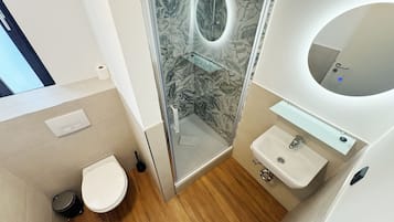 A modern bathroom with a toilet, shower, and sink.