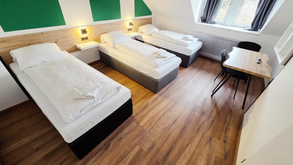 A hotel room with two beds, a small table, and a chair.