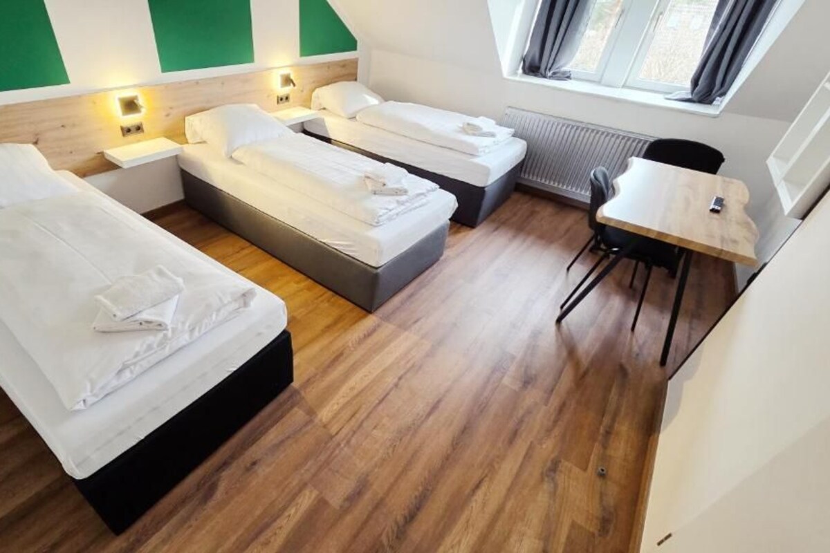 A hotel room with two beds, a small table, and a chair.