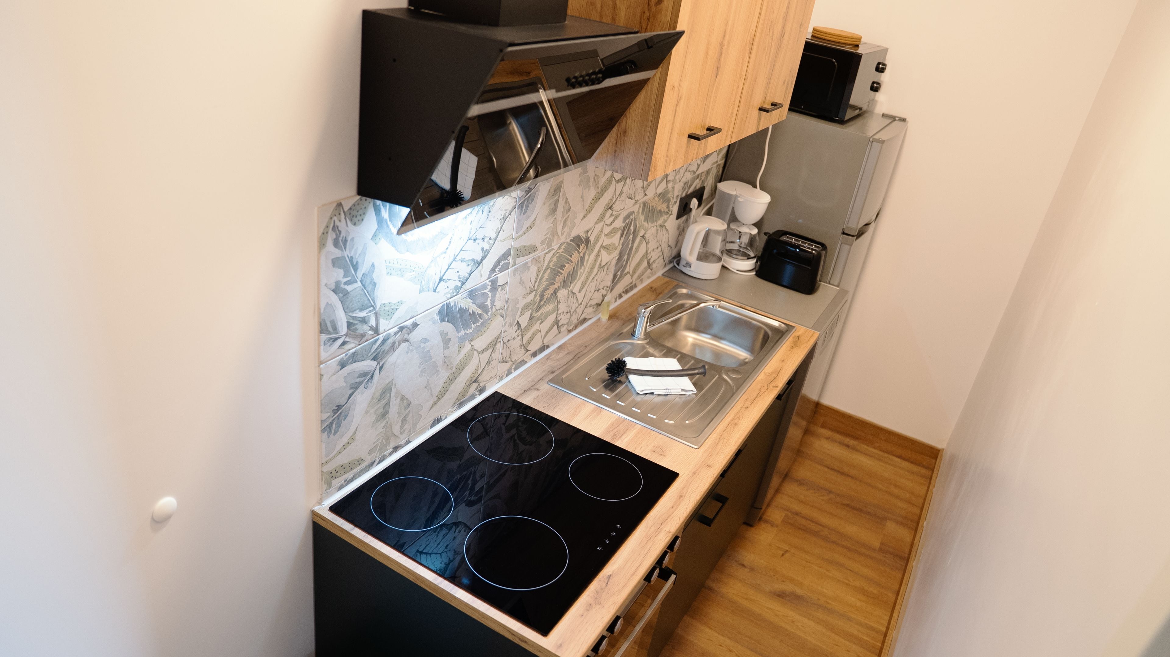 A compact kitchen with a built-in stove, a sink, and a microwave.