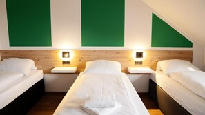 A hotel room with two beds, a wooden headboard, bedside lamps, and green wall panels. - Hive Apartments Lühnde (Algermissen)