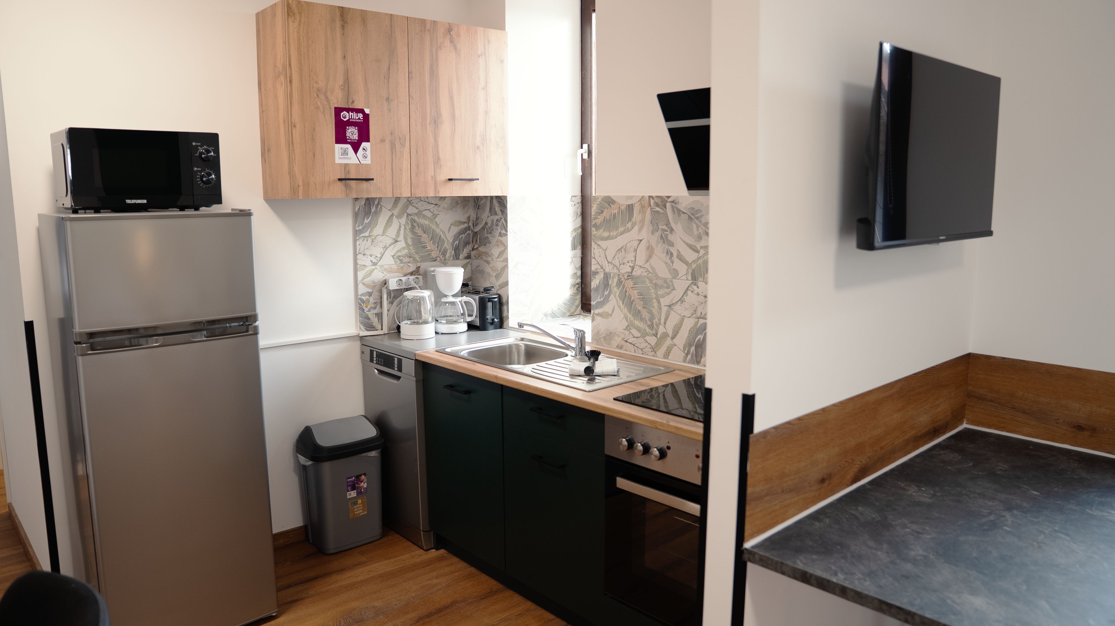 A compact kitchen with a refrigerator, microwave, sink, and a small stove.