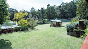 A fenced backyard with a gazebo, a wooden deck, and a variety of trees and shrubs. - Pemby Nest (Pemberton)