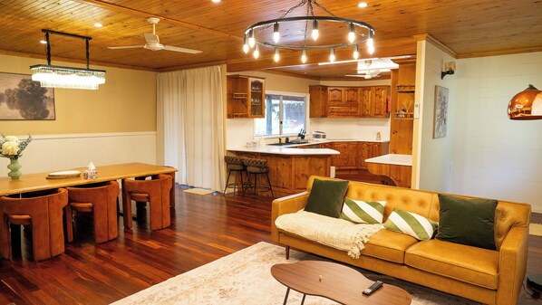 A cozy living room with a sofa, a dining area with a table and chairs, and a kitchen with wooden cabinets.