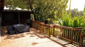 A wooden deck with a covered seating area and a barbecue grill.