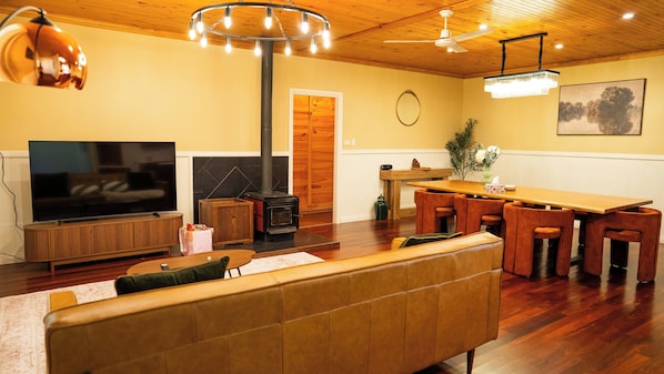 A cozy living room with a large flat-screen TV, a fireplace, and a dining area with wooden furniture.
