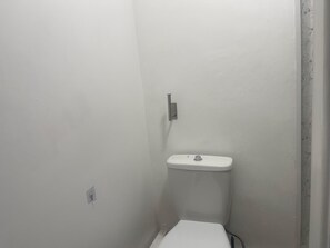 A small, white bathroom with a toilet and a wall-mounted sink. -  A Studio apartment with a fully equipped kitchenette and Bathroom (Mitcham)