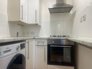 A compact kitchen with a built-in washer, a stove, and an oven. -  A Studio apartment with a fully equipped kitchenette and Bathroom (Mitcham)
