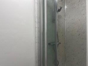 A glass-enclosed shower stall with a marble wall. -  A Studio apartment with a fully equipped kitchenette and Bathroom (Mitcham)