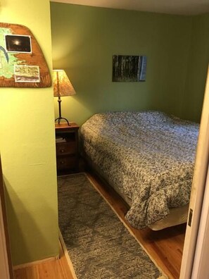 A bedroom with a bed, a nightstand, a lamp, a map on the wall, and a painting. - Chadlington 2D - Newly remodeled, Near the slopes (Mt. Crested Butte)