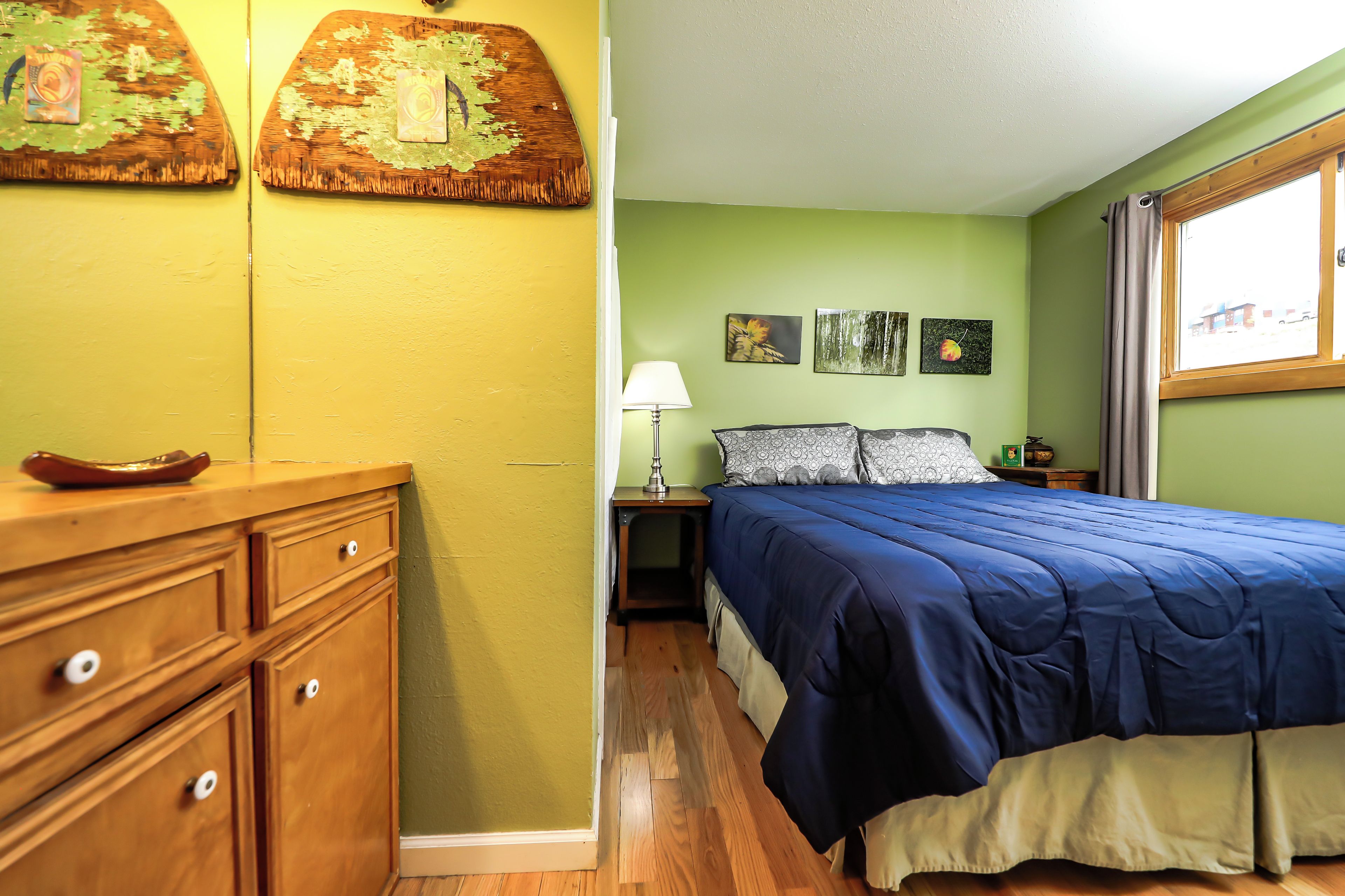 Une chambre avec un lit, une table de chevet, une lampe et une commode.