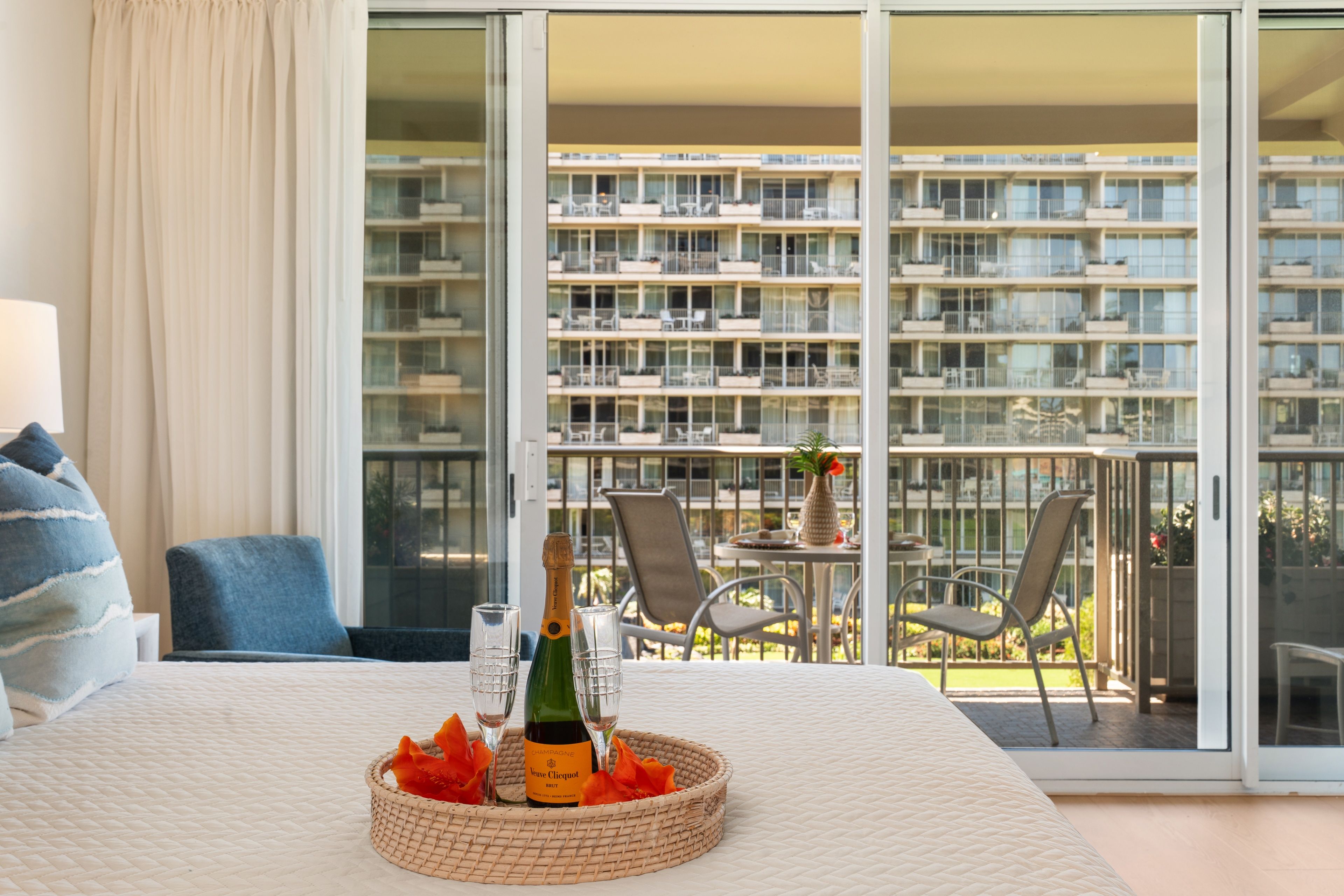 Un balcón con una mesa lista para dos personas, con vista a un edificio residencial.