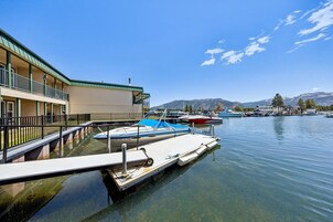 Un puerto deportivo con barcos amarrados, un edificio con balcón y montañas al fondo.