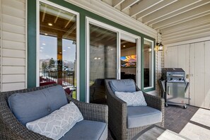 Ein überdachter Patio-Bereich mit Korbstühlen und einem Grill.