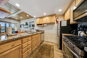 Una cocina con armarios de madera, un refrigerador de acero inoxidable, una estufa a gas y un microondas.