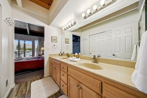 Un baño con lavamanos doble, muebles de madera, un espejo grande y vistas a un balcón.