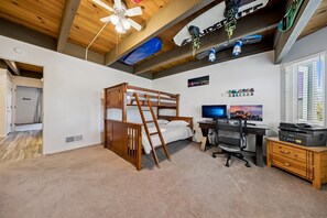 Un dormitorio con literas, un escritorio con computadora, una silla y una ventana con persianas.