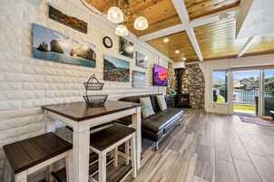 Un interior acogedor con chimenea de piedra, techo de madera y una zona de comedor con banco y mesa.