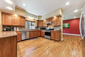 A kitchen with wooden cabinets, stainless steel appliances, and a red accent wall. - 2291 Sutter Trail 4 Bedroom Home (South Lake Tahoe)