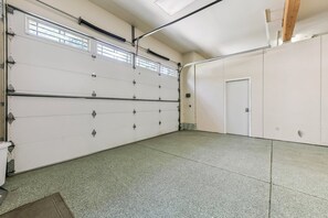 A garage with a large white door, a concrete floor, and a wooden ceiling beam. - 2291 Sutter Trail 4 Bedroom Home (South Lake Tahoe)
