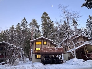 A two-story building with a balcony, surrounded by snow-covered trees and a clear sky. - 3388 Pine Hill Road 2 Bedroom Home (South Lake Tahoe)