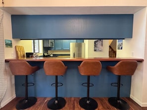 Eine Küche mit blauer Spritzschutzwand, einer Holz Arbeitsplatte und drei Barhocker.