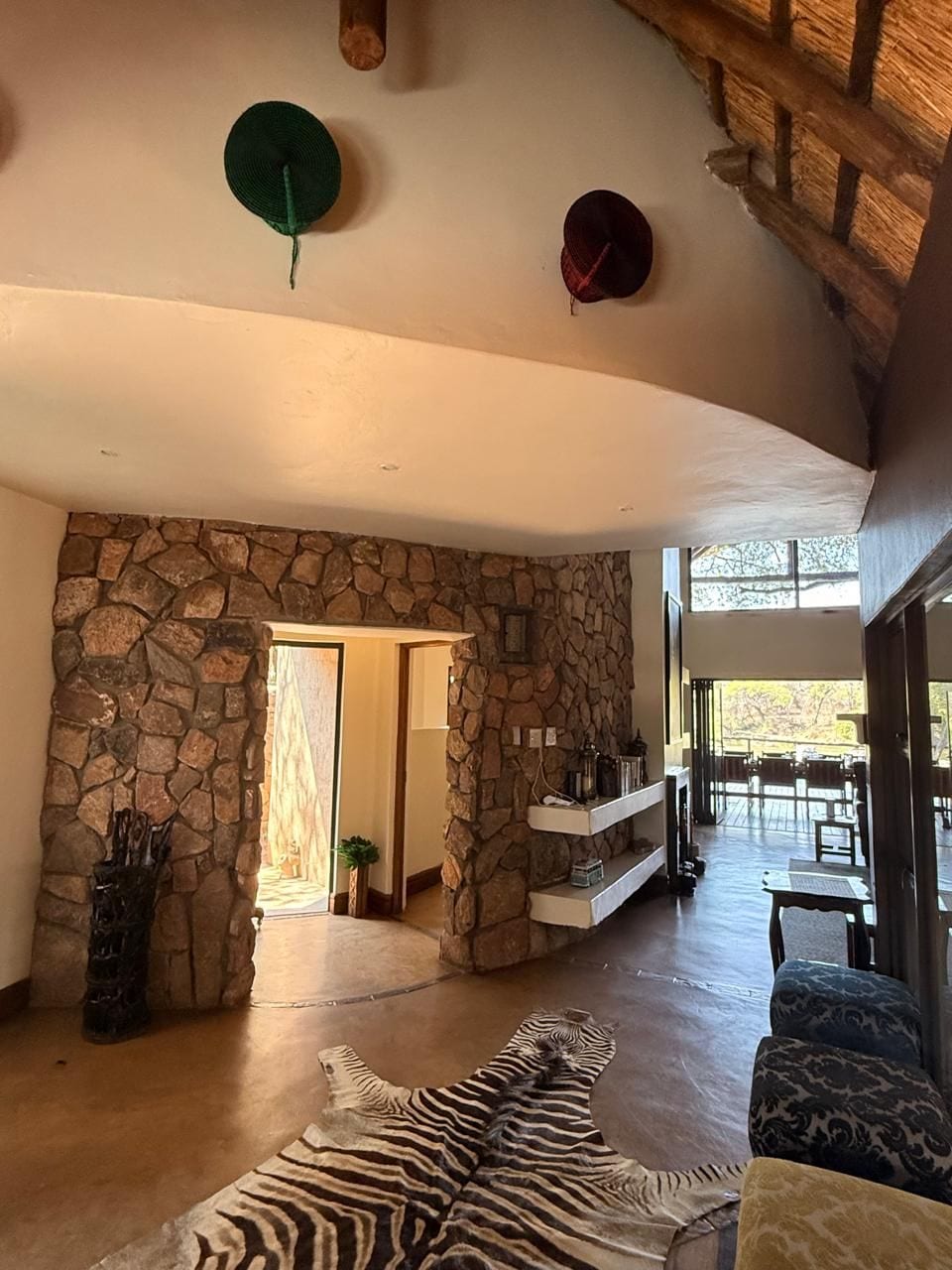 Un espacio habitable amplio con una pared de piedra, un tapete de cebra y un techo de madera.