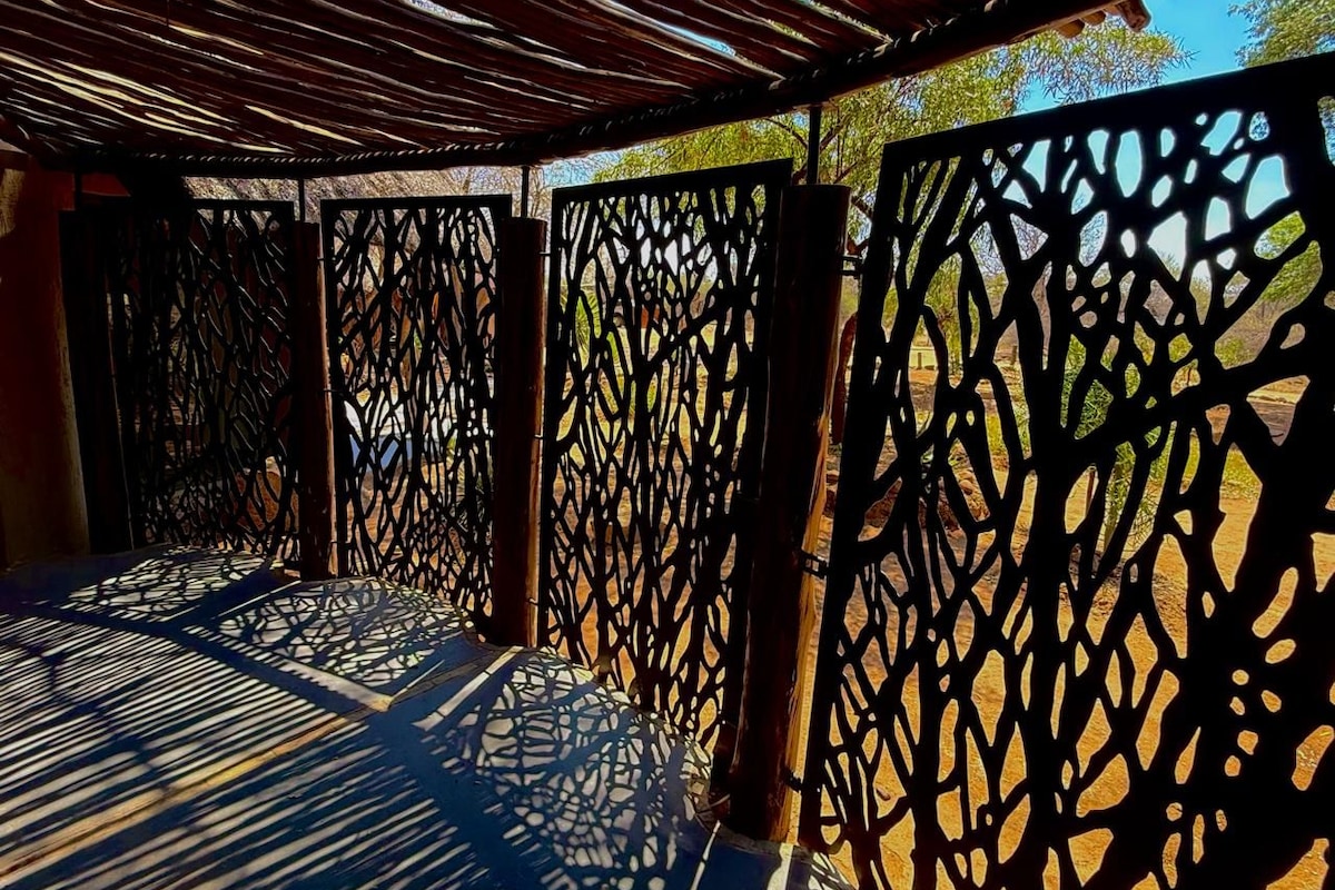 A covered outdoor area with patterned metal railings and a wooden floor.