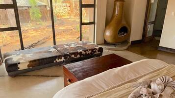 Una habitación con una cama, un banco de madera, una chimenea y vistas a un espacio exterior.