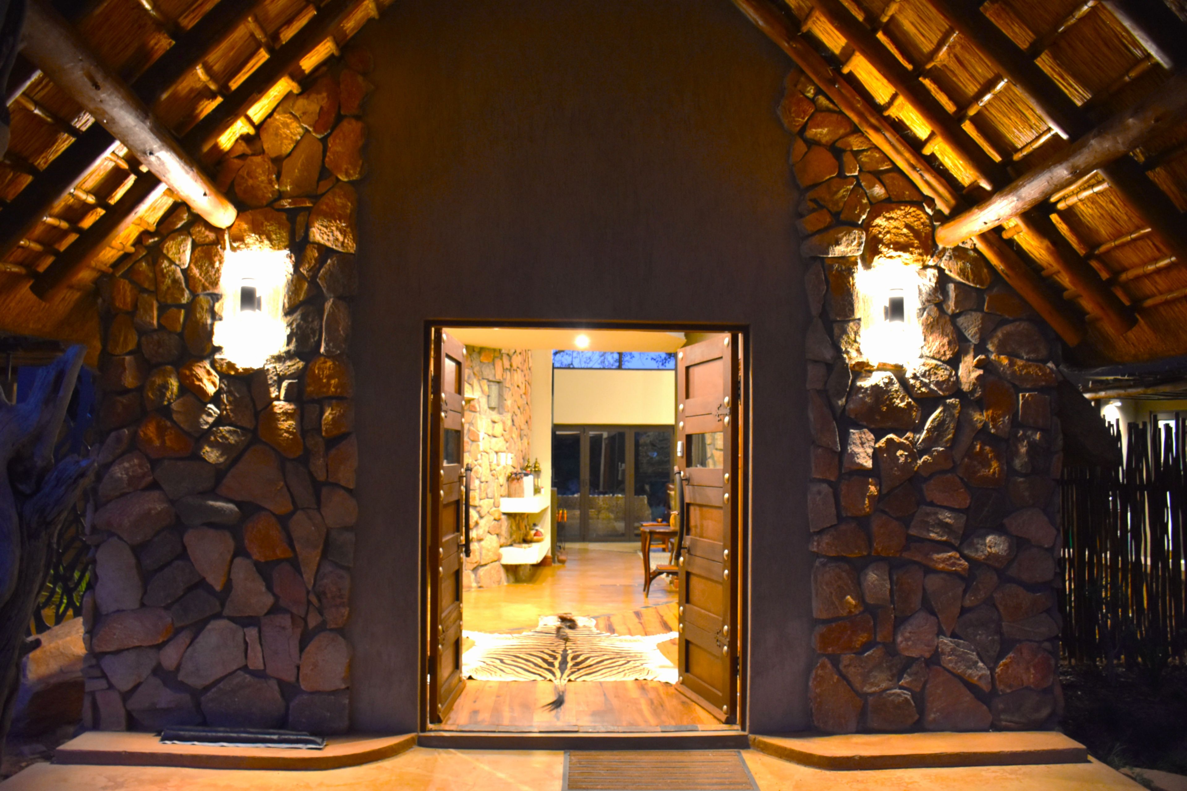 Une entrée en pierre avec un plafond en bois et deux appliques murales.