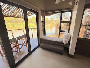 A room with a bed, large windows, and a view of a water body.