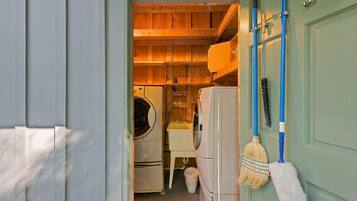 A laundry room with a washing machine, dryer, and broom.