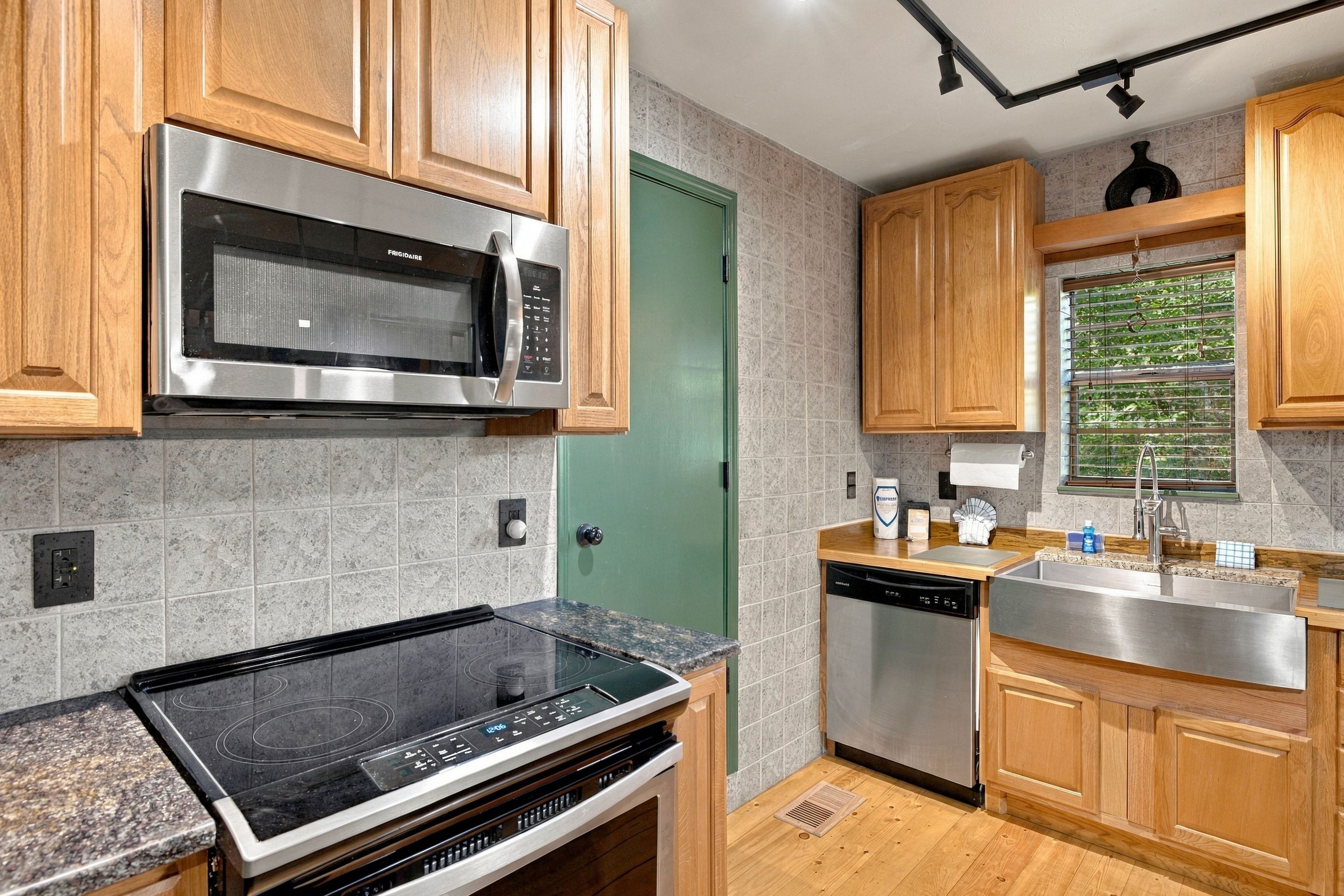 Una cocina moderna con electrodomésticos de acero inoxidable, armarios de madera y una puerta verde.