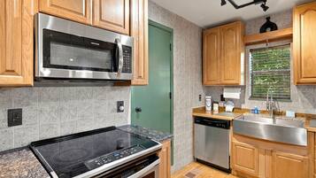 Una cocina moderna con electrodomésticos de acero inoxidable, armarios de madera y una puerta verde.