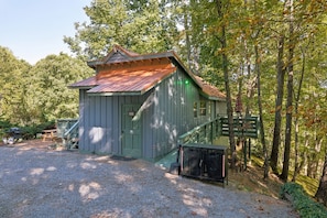 A rustic cabin with a green door, a small porch, and a gravel driveway. - Hideaway Overlook 1 Bedroom Cabin (Sevierville)