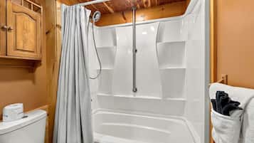 Un baño con ducha, inodoro y armarios de madera.