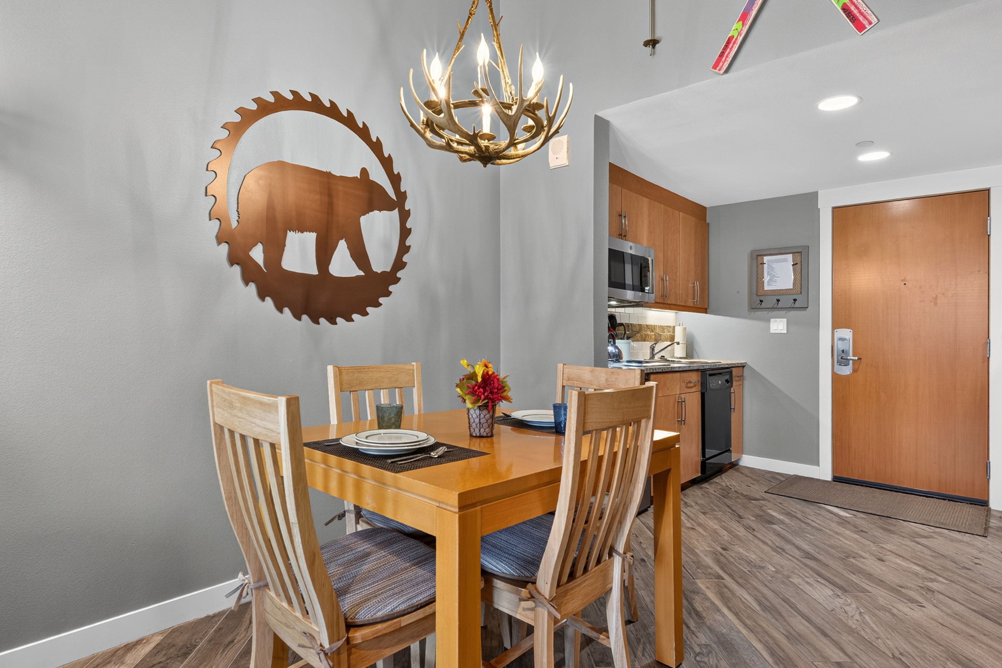 Un coin repas avec une table en bois, des chaises et une silhouette d’animal fixée au mur.