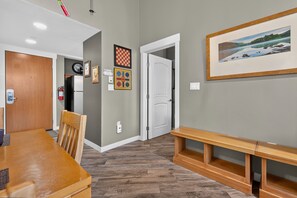 A hallway with a wooden bench, a dining area with a table and chairs, a fire extinguisher, and a framed picture on the wall. - Premium Unit 3623 - 1 Br W/kitchenette 1 Bedroom Condo (Winter Park)