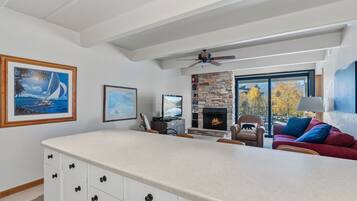 Een moderne keuken met een groot eiland, een open haard en een zithoek met een rode bank.