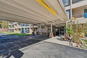 Une entrée d’immeuble dotée d’un espace abrité, d’un banc en pierre et offrant une vue dégagée sur la façade de l’immeuble.
