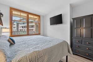 A bedroom with a bed, a TV mounted on the wall, and a wardrobe. - Premium Unit 1320 - 1 Br - Zephyr Mountain Lodge 1 Bedroom Condo (Winter Park)