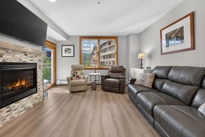 A living room with a fireplace, a sofa, a recliner, and a window with blinds. - Premium Unit 1320 - 1 Br - Zephyr Mountain Lodge 1 Bedroom Condo (Winter Park)