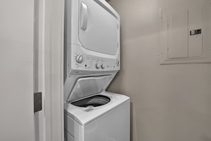 A front view of a white wall-mounted washer and dryer unit with control knobs and a door. - Premium Unit 3301 - Two Bedroom - Fraser Crossing/Founders Pointe 2 Condo (Winter Park)